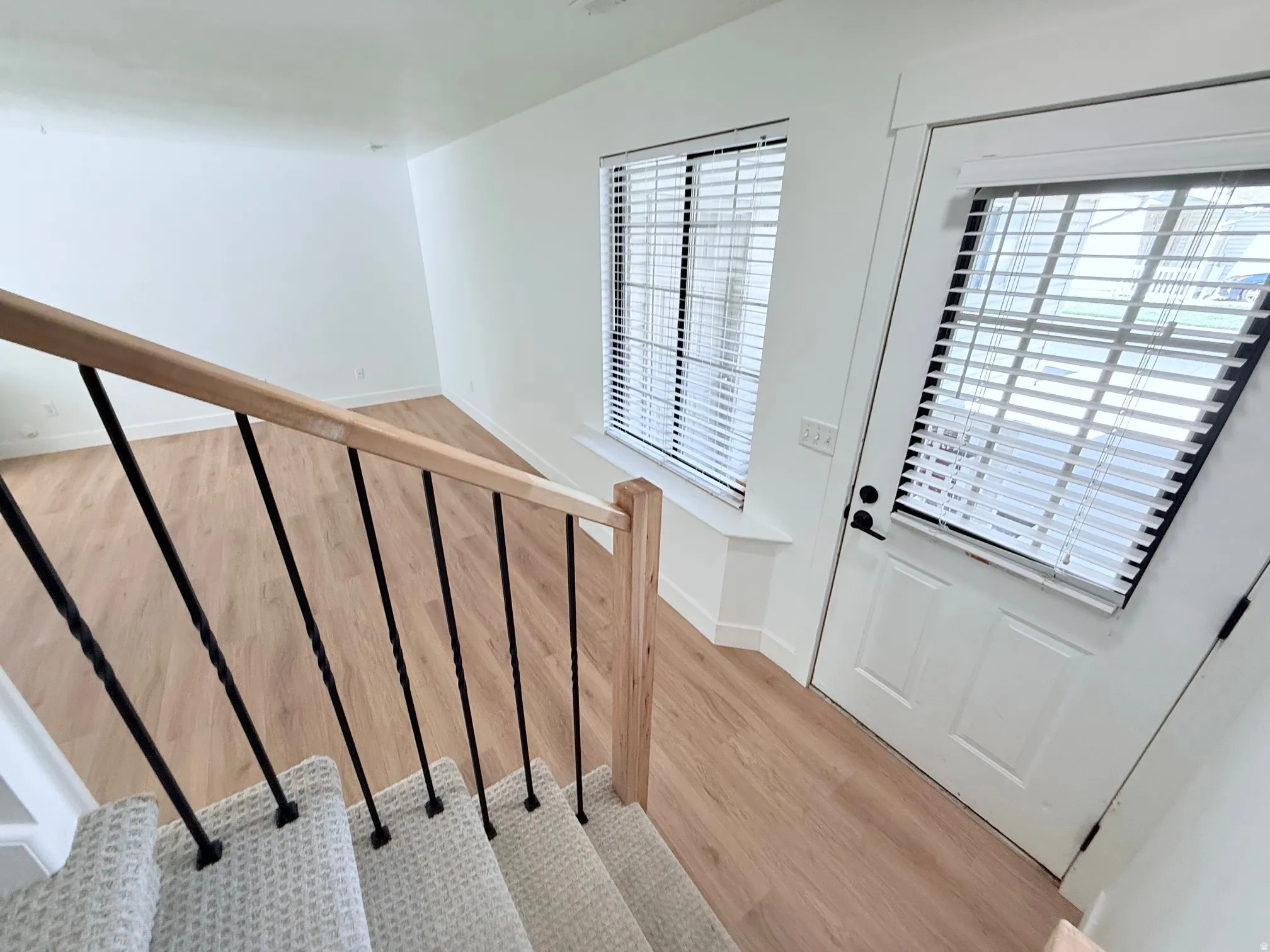 Light wood-finish flooring, white walls, and a window with blinds