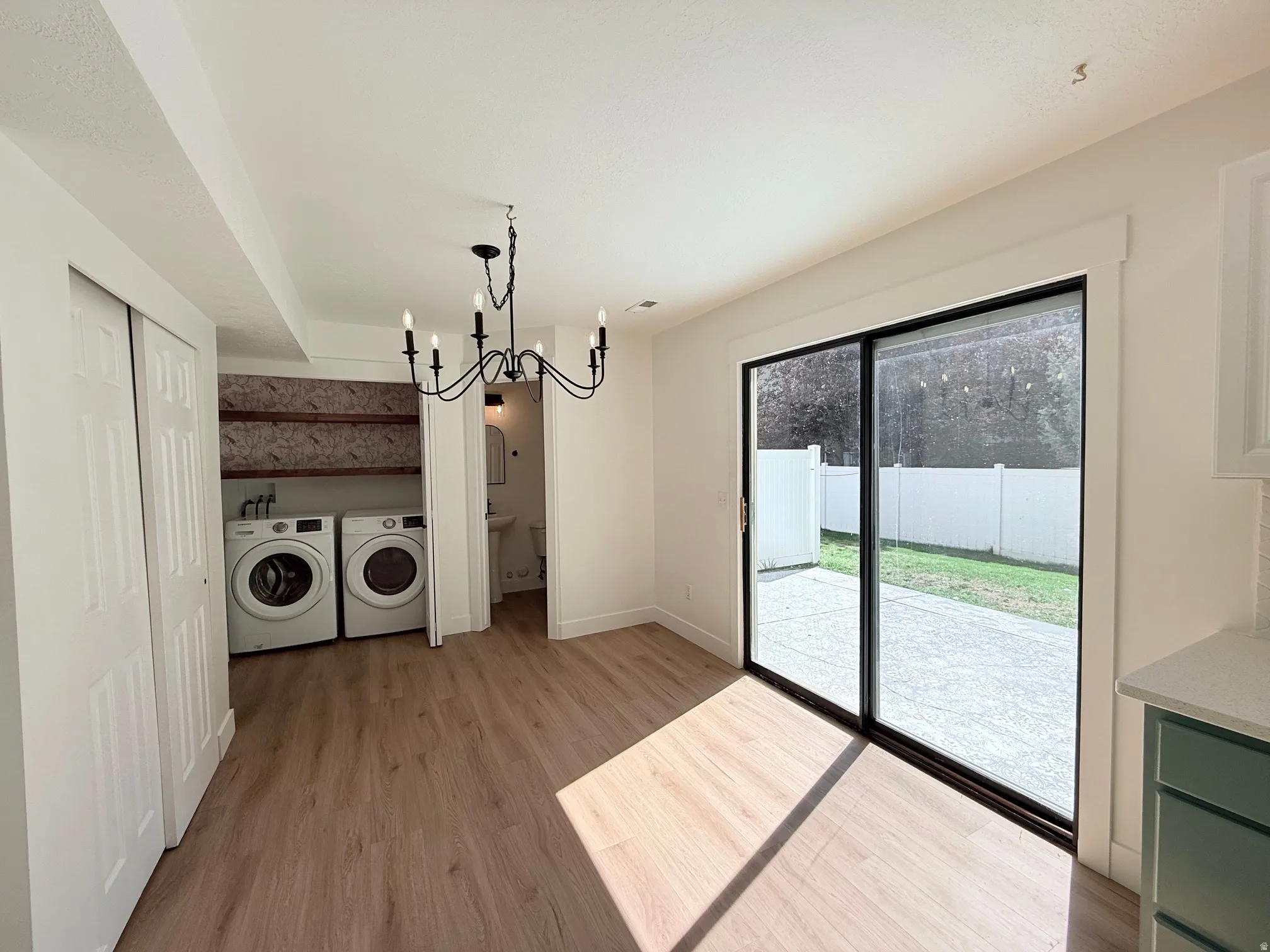 Wood-finish flooring throughout, a black iron chandelier, and a built-in laundry area with shelving
