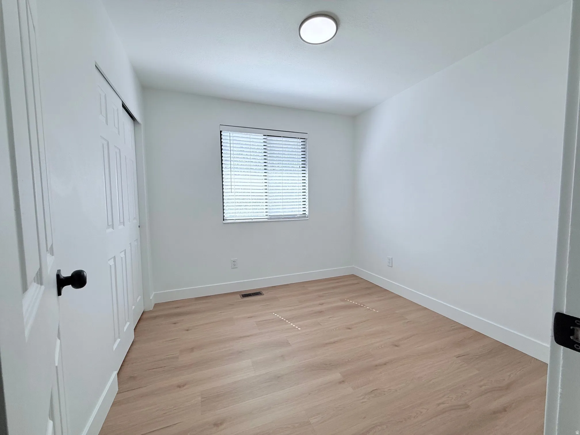 Light wood-finish flooring, white walls, and a window with blinds provide a bright interior