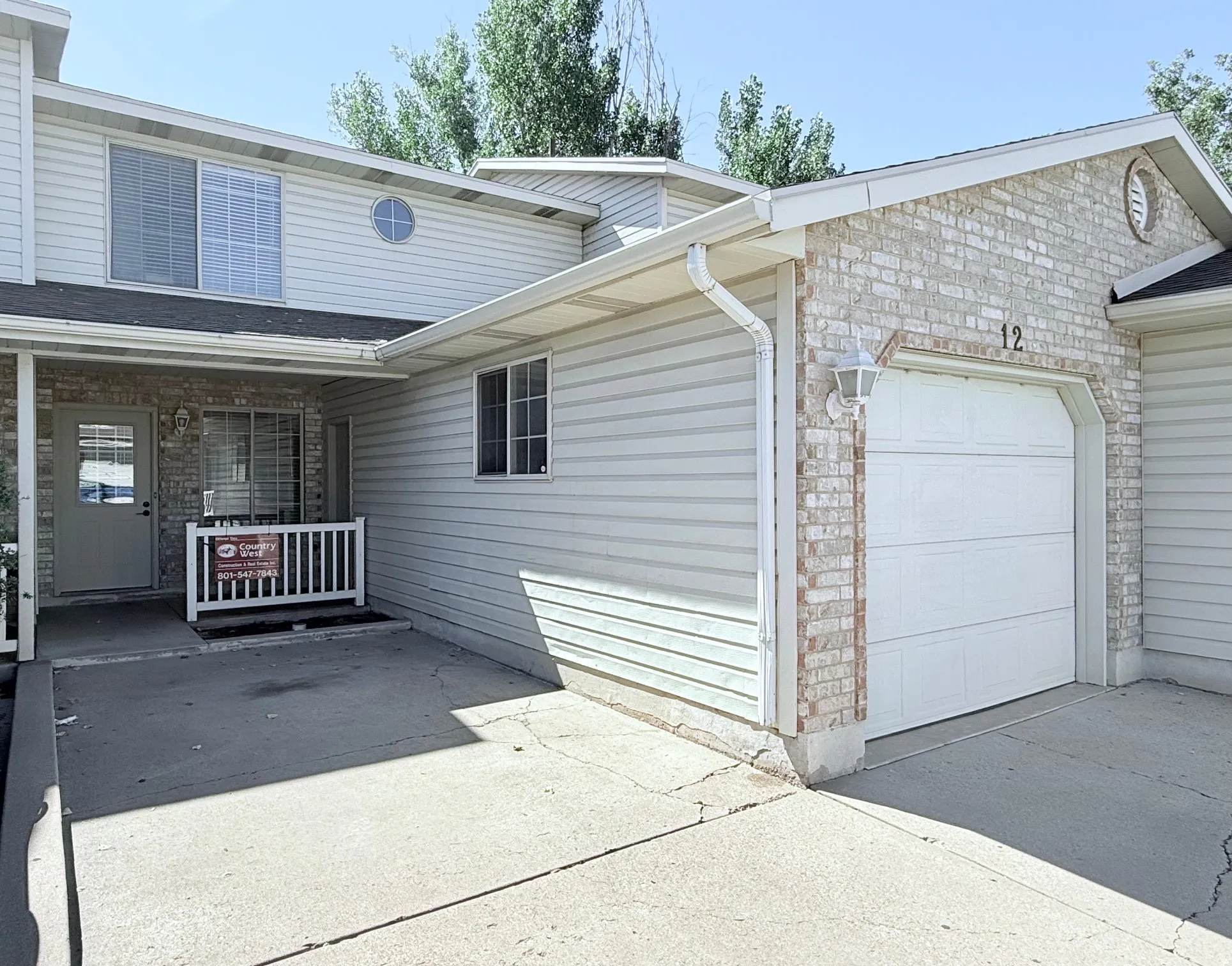 Attached single-car garage, light-toned brick facade, horizontal siding, and a covered entry