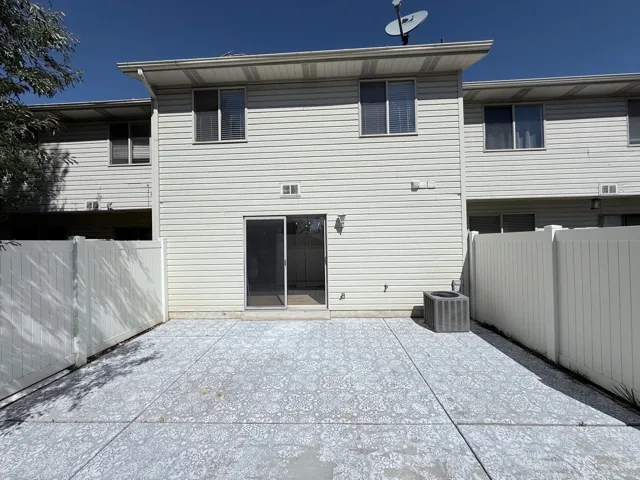 Spacious patio featuring light-colored concrete pavement, bordered by metal fencing on both sides
