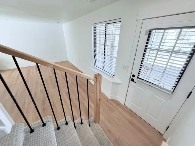 Light wood-finish flooring, white walls, and a window with blinds