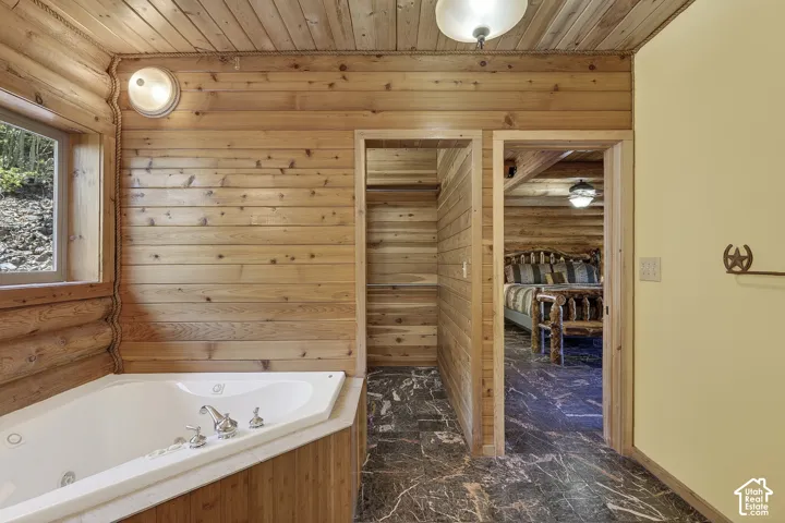 Corner jetted tub with chrome fixtures, surrounded by natural wood paneling
