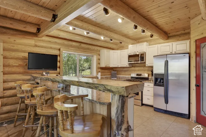 Kitchen featuring natural log walls, wood-finish ceiling, and exposed log beams