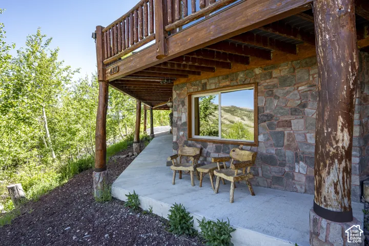 Stone veneer exterior with a concrete patio featuring natural wood support columns