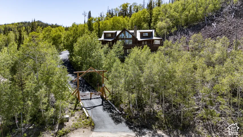 Mountain retreat featuring a log cabin aesthetic, a gabled roof, and extensive natural landscaping
