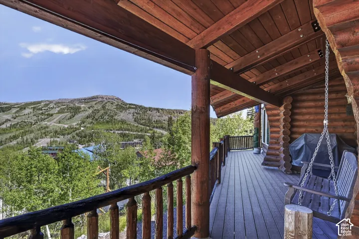 Expansive log cabin-style deck featuring natural wood-finish flooring, exposed wood beams, and a railing system