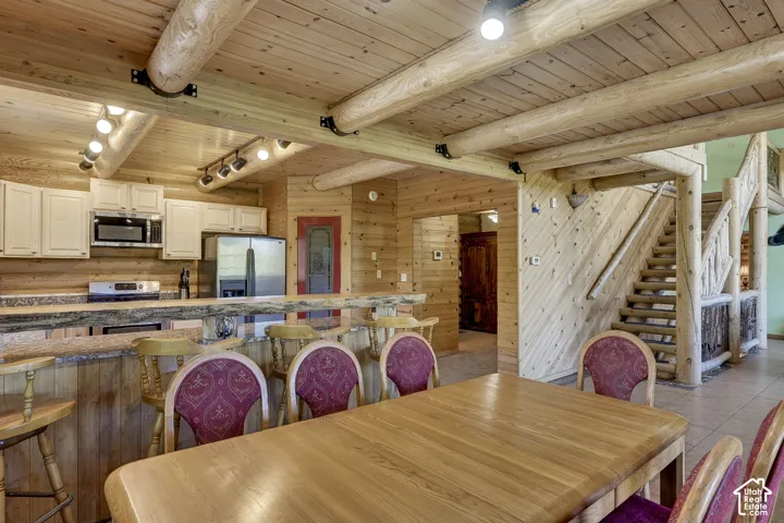Open-concept living area featuring extensive wood-finish walls and ceilings with exposed log beams