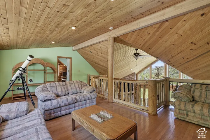 Expansive loft area featuring wood-finish flooring, a full wood plank ceiling, and a rustic log railing overlooking the space below