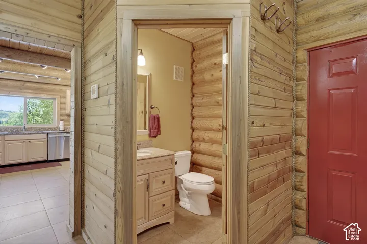 Bathroom featuring a light wood-finish vanity with a light-colored countertop, a wall-mounted light fixture, and a toilet