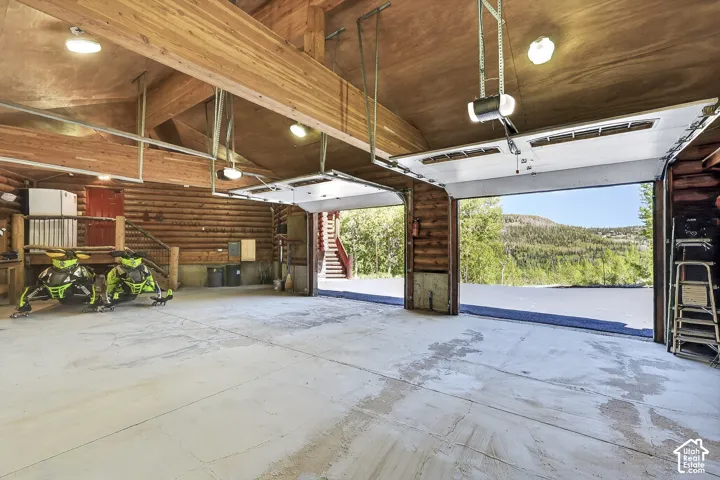Spacious garage featuring exposed wood beam construction, durable concrete flooring, and multiple automatic garage doors