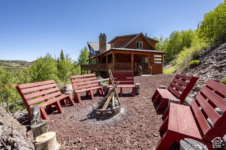 Outdoor fire pit area with red benches and a gravel base, set against a backdrop of mature trees