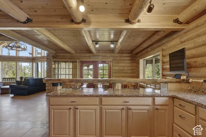 Kitchen featuring granite-style countertops, light wood cabinetry, and a natural wood breakfast bar