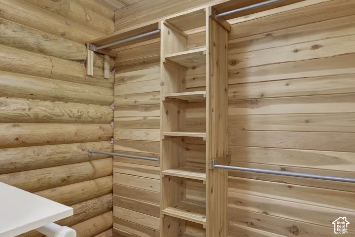 Custom wood shelving system and hanging rods in a wood-paneled space