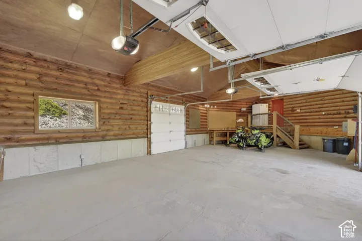 Spacious garage featuring log-style walls, a concrete floor, and two overhead garage doors