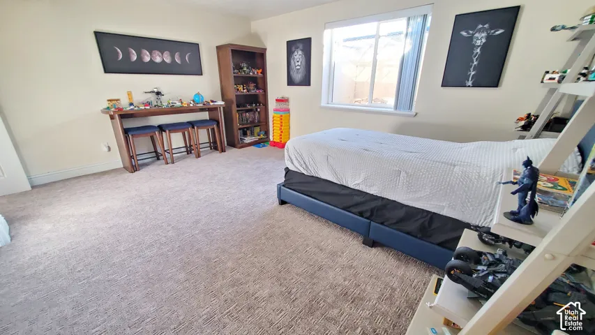 Carpeted room featuring a window with vertical blinds, light-toned walls, and a built-in wooden bookcase