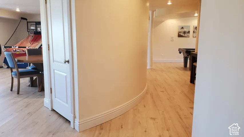 Curved interior wall with light wood-finish flooring, white baseboards, and overhead recessed lighting