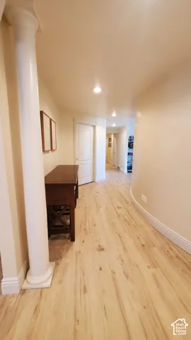 Long hallway featuring wood-finish flooring, recessed lighting, and a decorative column with capital and base