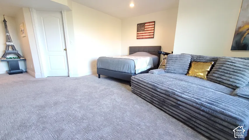 Neutral tone wall paint, light-colored carpet flooring, recessed lighting, and a white interior door with a brass-finish doorknob