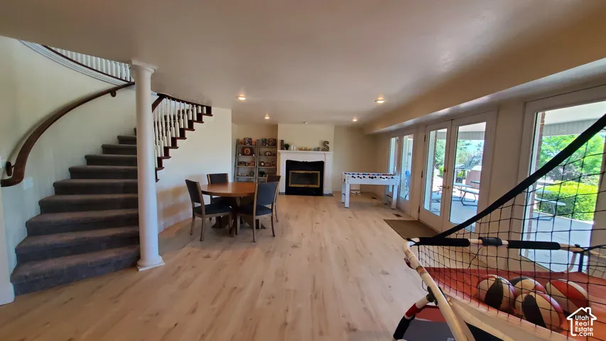 Spacious interior featuring a curved staircase with white balusters, light wood-finish flooring, and multiple sets of French doors