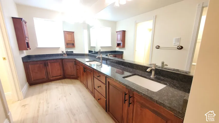Spacious vanity area featuring light wood-finish flooring