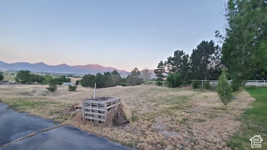 Expansive property featuring a scenic mountain backdrop, mature trees, and a partial white fence border