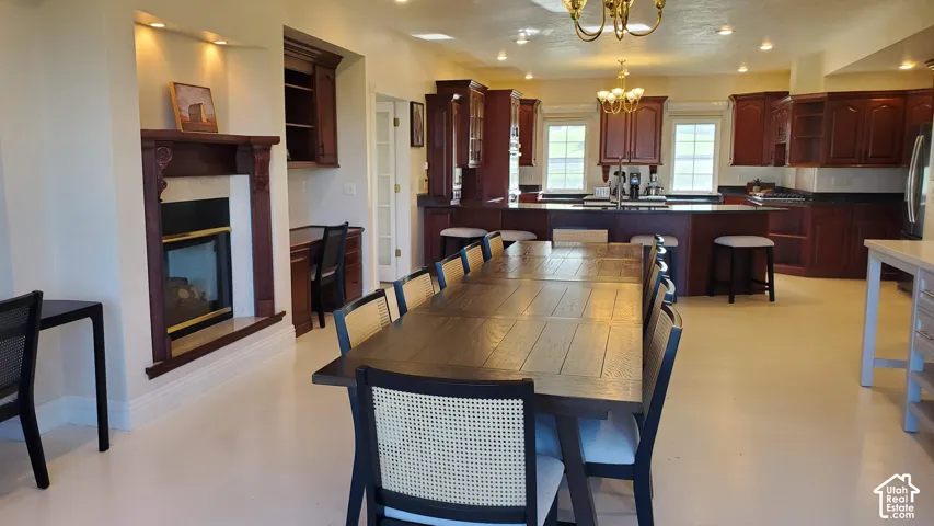 Open-concept living space featuring a gas fireplace with a wood mantle, built-in desk, wood cabinetry, an island with seating, and light-toned flooring