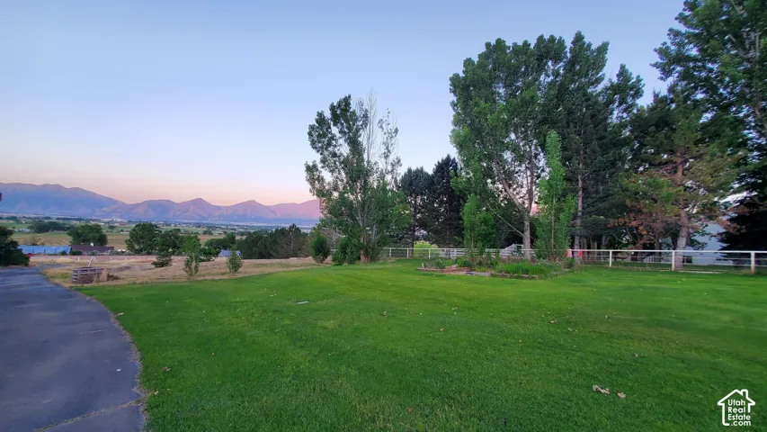 Expansive green lawn with mature trees and a distant mountain range backdrop