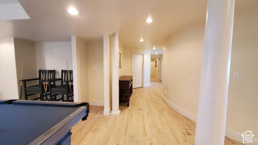 Recessed lighting illuminates a spacious area featuring wood-finish flooring, a decorative column, and painted walls