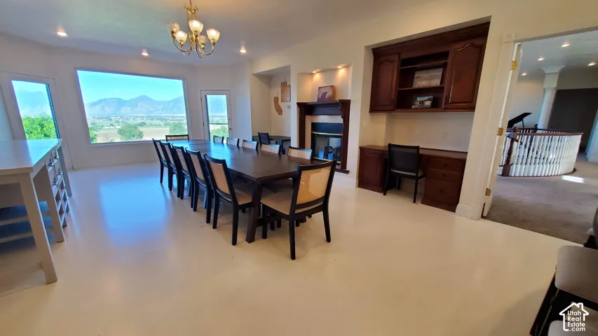 Spacious room featuring multiple windows, a built-in fireplace, a built-in desk with cabinetry, light-toned flooring, and a chandelier
