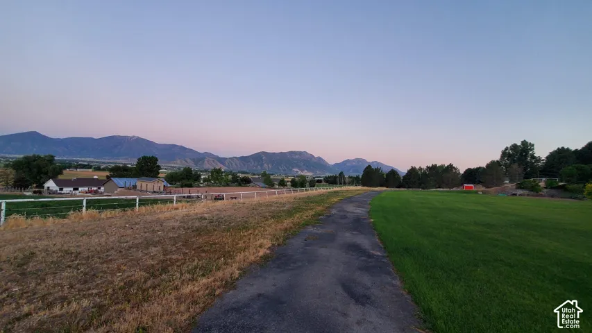 Expansive grounds featuring a paved pathway, manicured green lawn, and distant mountainous terrain