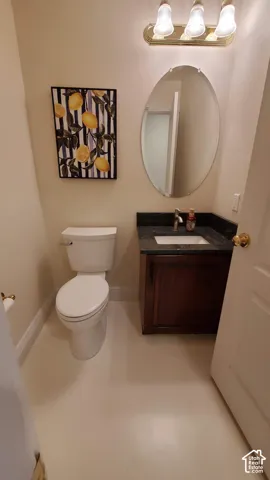 Powder room featuring a dark wood vanity with a dark granite countertop, undermount sink, and oval mirror