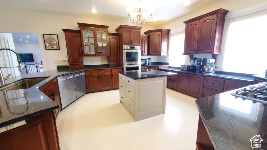 Spacious kitchen featuring dark wood cabinetry, a central island with white paneling, stone countertops, and recessed lighting