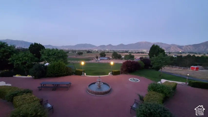Expansive outdoor patio with red brick-patterned hardscaping and a multi-tiered water fountain