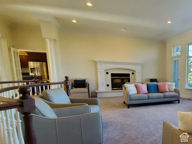 Expansive living area with large bay windows, recessed lighting, crown molding, a decorative fireplace, and a light-toned balustrade