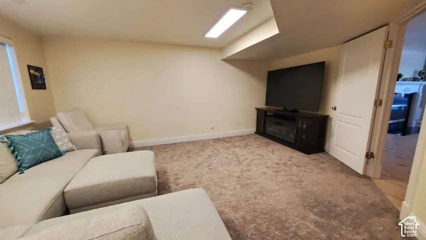 Carpeted recreation room featuring neutral wall finishes and a built-in entertainment console with an electric fireplace