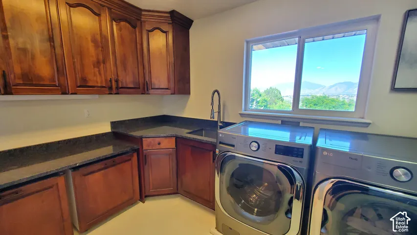 Laundry room featuring wood cabinetry, dark granite countertops, and a built-in sink with a gooseneck faucet