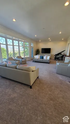 Spacious gathering room featuring a large bay window, recessed lighting, patterned carpet, and direct outdoor access