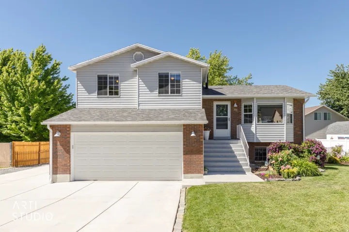 Split-level residence featuring a two-car garage, brick and siding exterior, and a manicured lawn