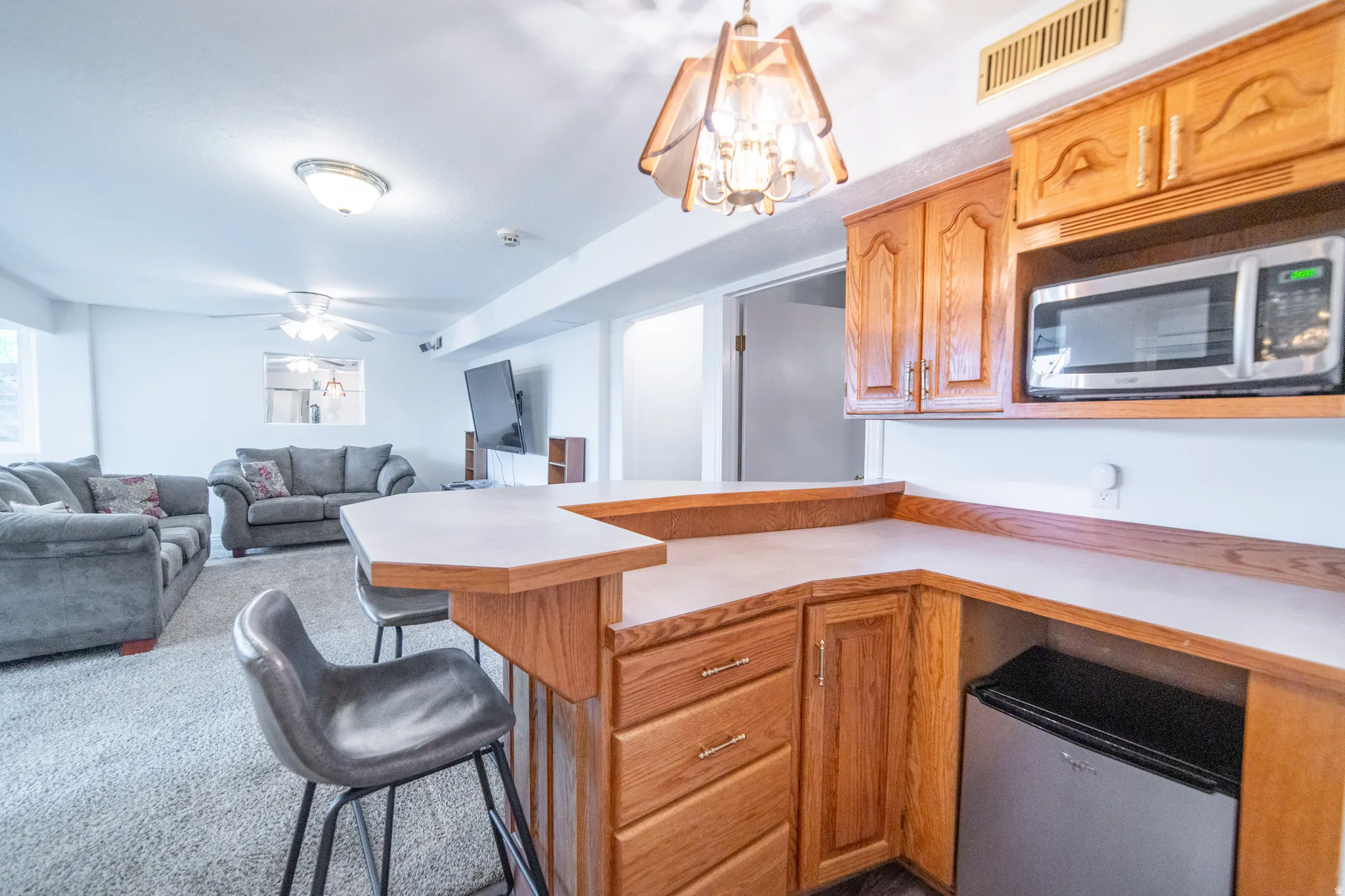 Bar featuring wood cabinetry, integrated microwave, and undercounter refrigerator