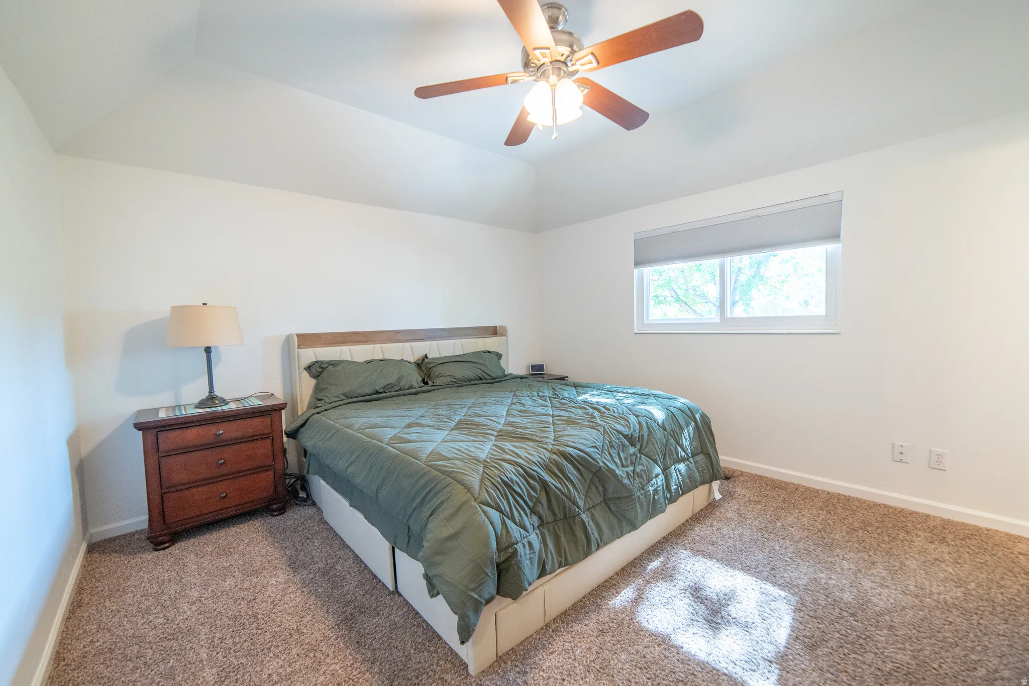 Spacious room featuring vaulted ceilings and neutral-toned carpeting