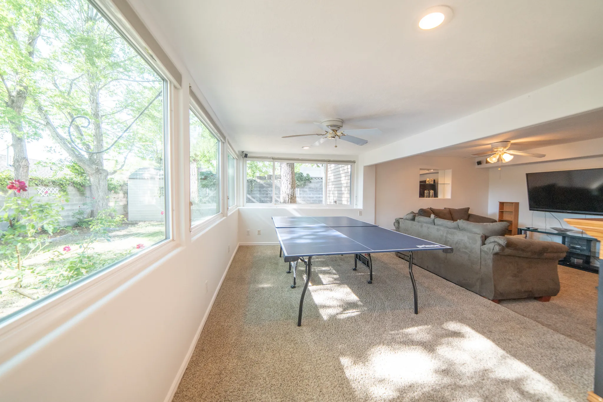 Carpeted recreation room featuring large windows, recessed lighting, and ceiling fans