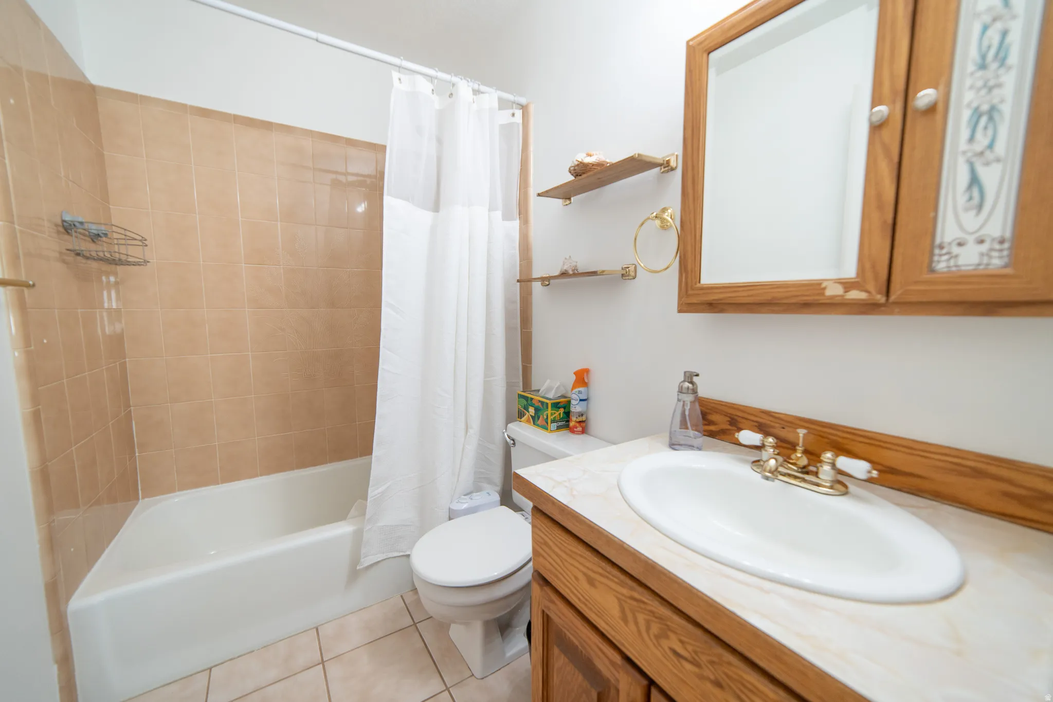 Bathroom vanity with a white oval sink, brass-finish faucet, and wood-finish cabinetry
