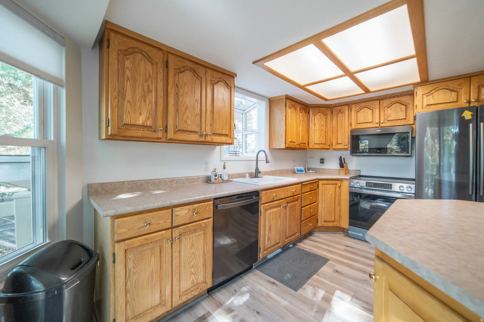 Kitchen featuring light wood cabinetry, laminate countertops, a stainless steel range, and a built-in microwave