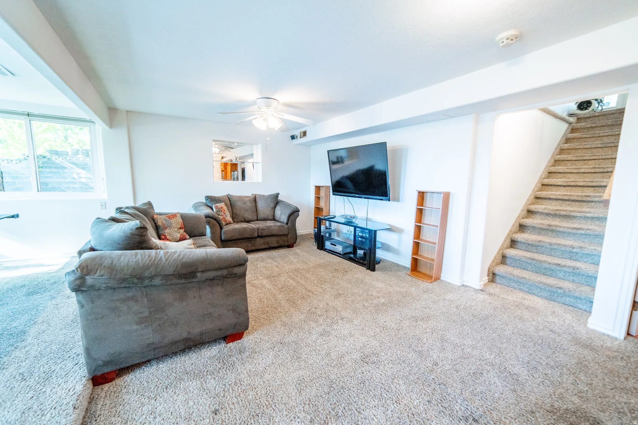 Carpeted interior space featuring white walls and a ceiling fan