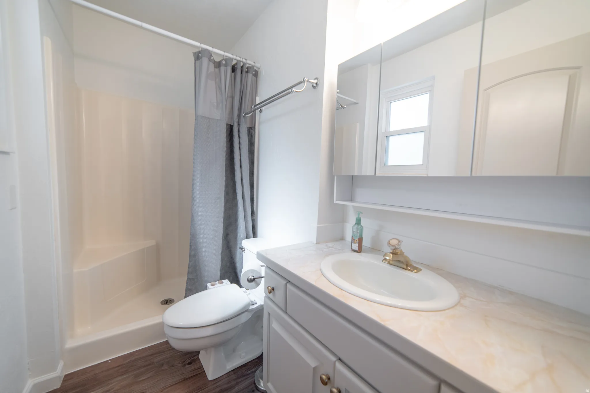 Bathroom featuring a single vanity with an oval sink, light-colored countertop, and a medicine cabinet with integrated shelving