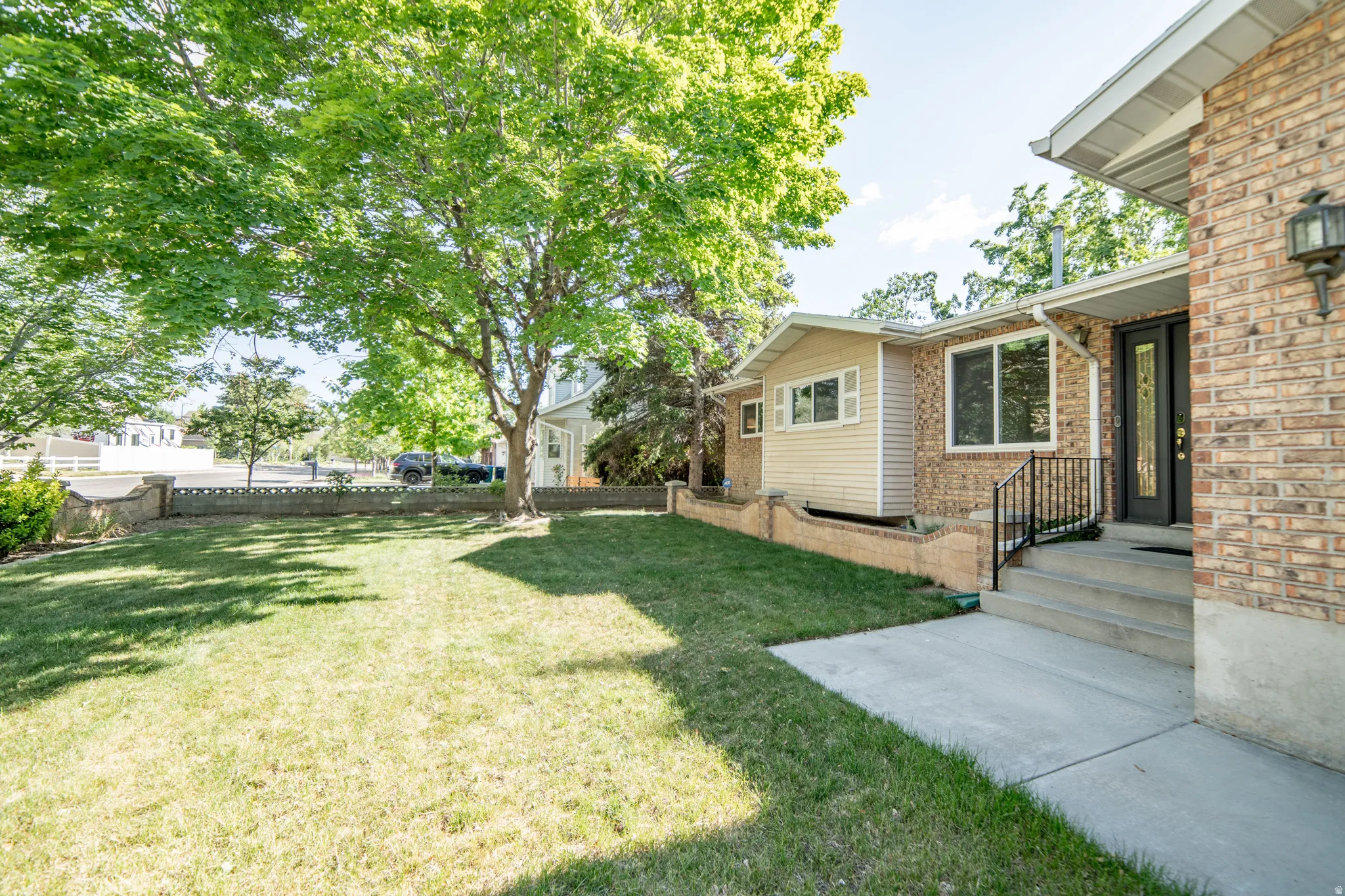 Brick and siding exterior with a concrete walkway and mature landscaping