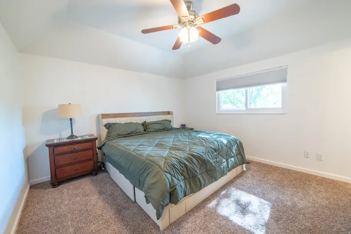 Spacious room featuring vaulted ceilings and neutral-toned carpeting
