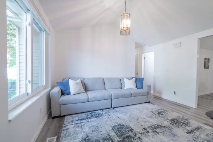Living area featuring vaulted ceilings, light wood-finish flooring, and a large picture window