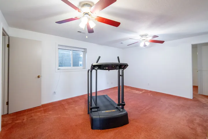 Spacious room featuring neutral white walls and red-hued carpeting